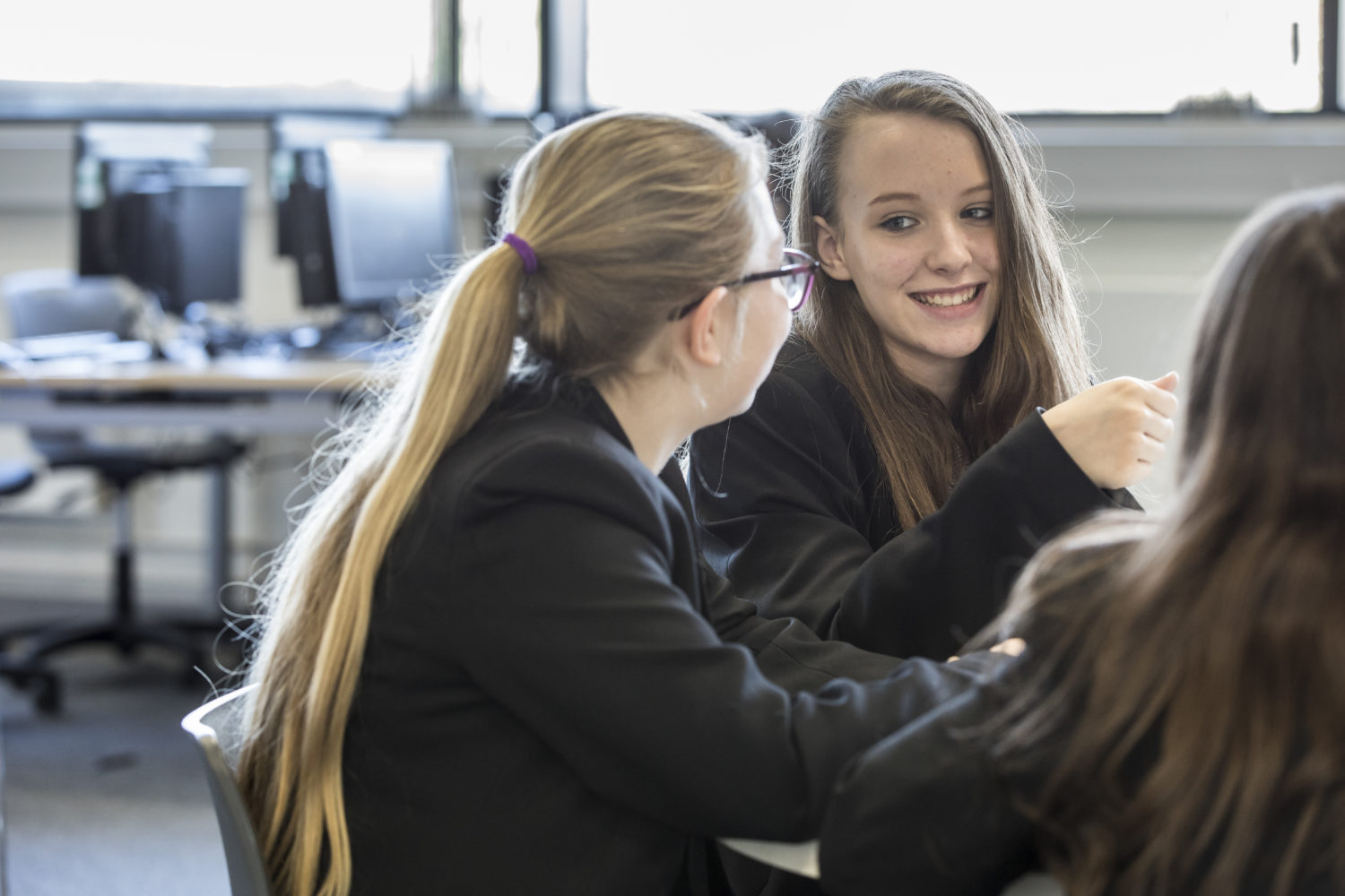 Three Strood Academy students are shown smiling together whilst working.
