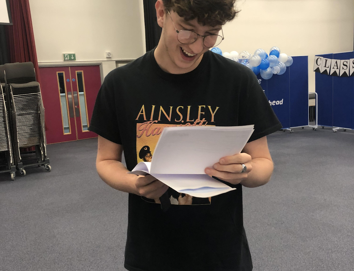 A Year 11 student is pictured opening up his GCSE Results and smiling.