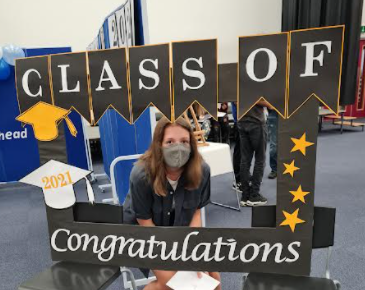 A Year 11 student poses for a photo with a banner reading "Congratulations Class of 2021" on GCSE Results Day.