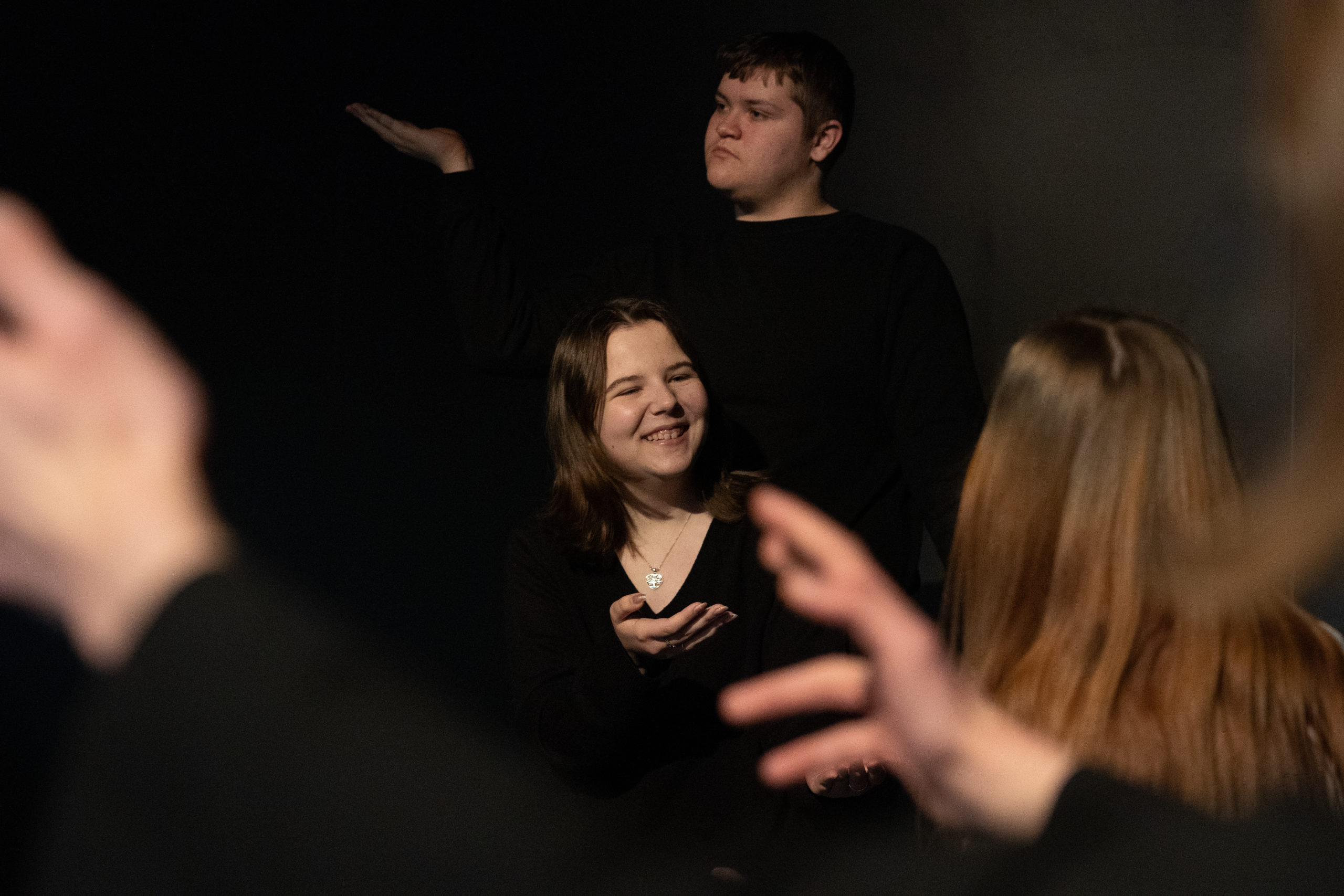 Four performing arts students in a drama studio acting and posing