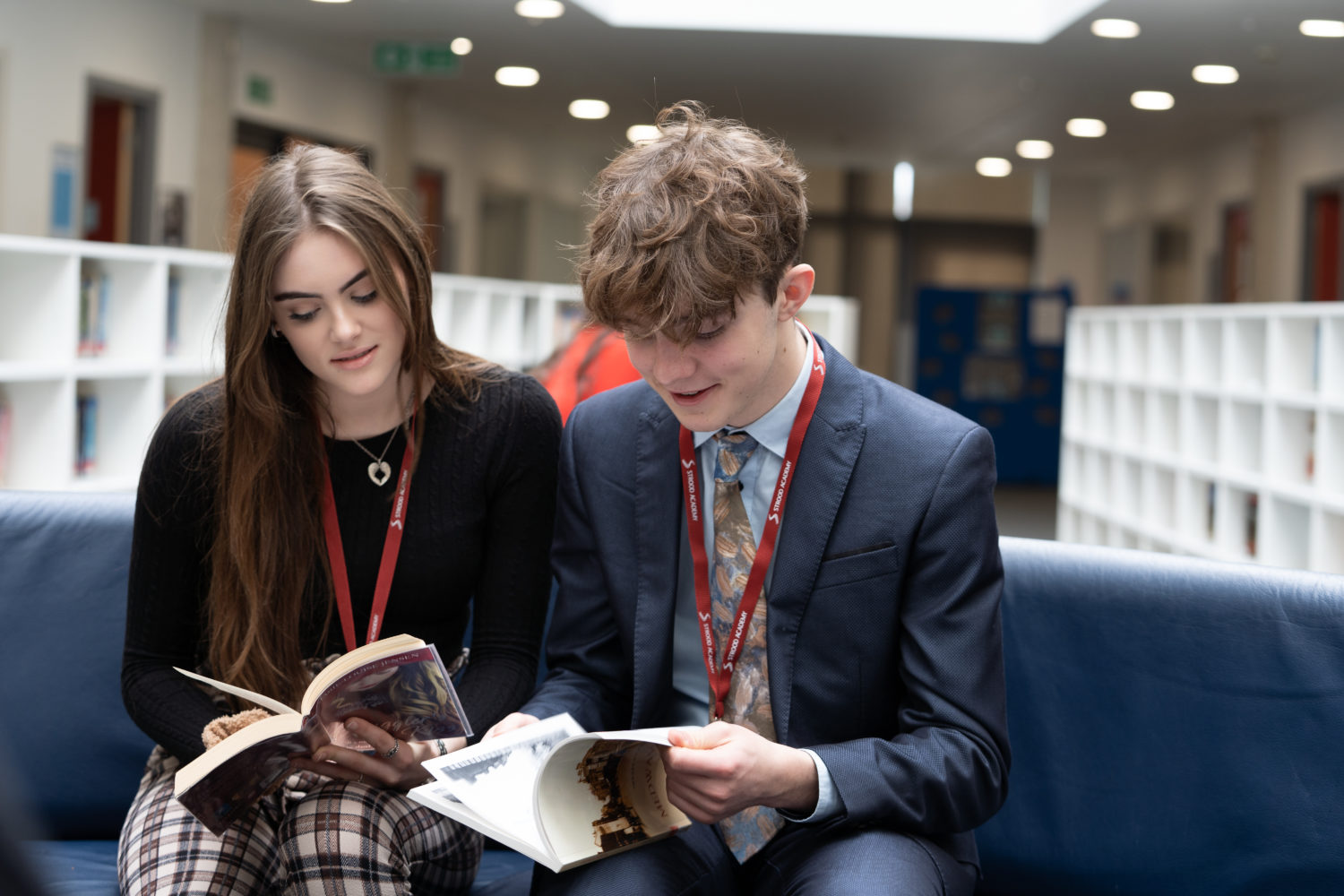 Two students reading two books in the library