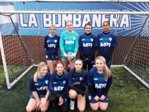 A team of girls wearing football kits smiling for a photo