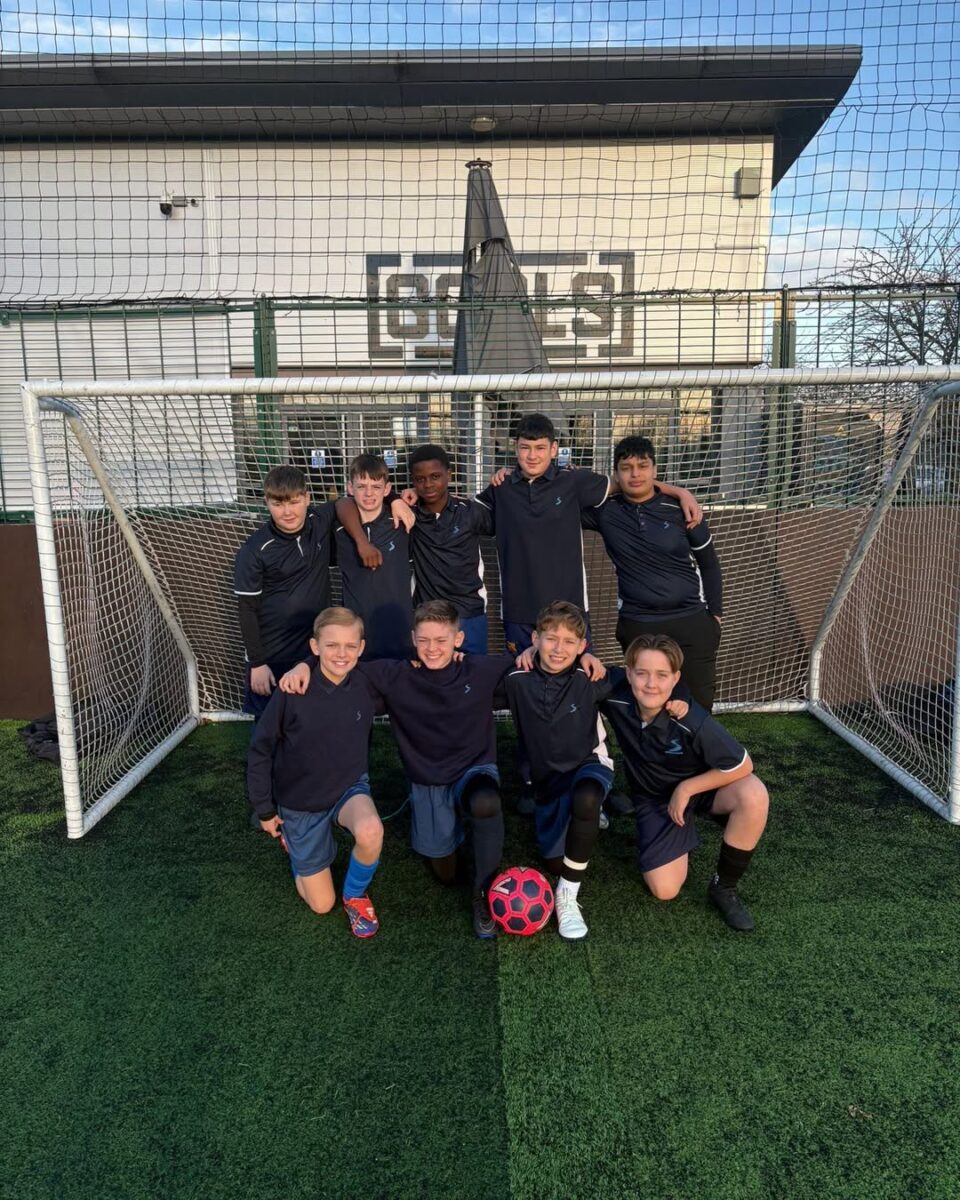 A team of boys smiling for a photo in a goal