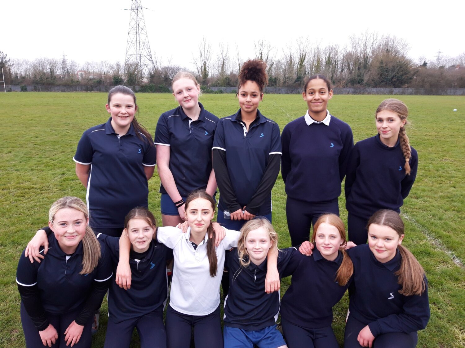 A team of girls wearing football kits smiling for a photo