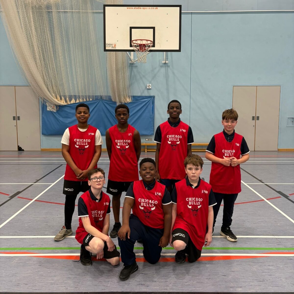 A team of students wearing basketball kits smiling for a photo