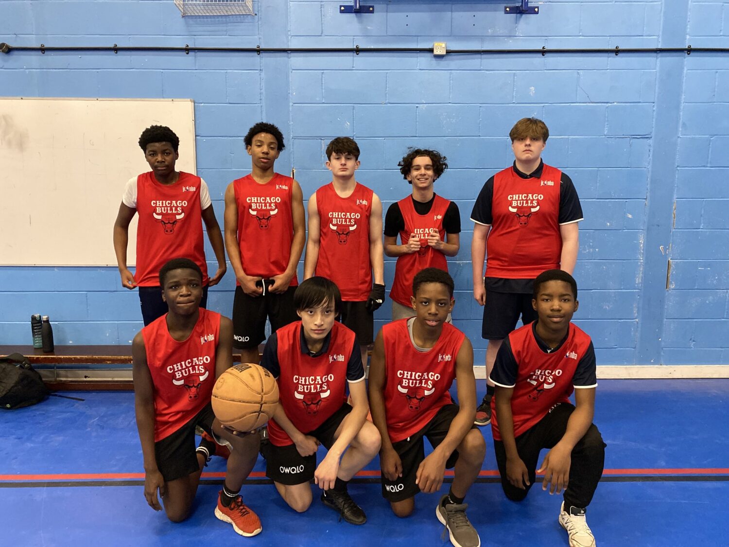 A team of students wearing basketball kits smiling for a photo