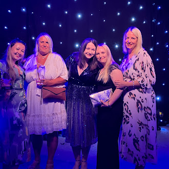 Five ladies on a stage with an award